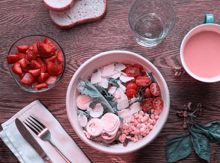 The same colorful salad in shades of red, pink, and greenish-blue. The orange juice appears pink, and the yellow corn and egg yolks appear less vibrant.